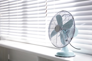 Photo of Modern electric fan on window sill indoors. Space for text