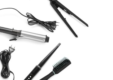 Image of Different hair irons and brush on white background, top view