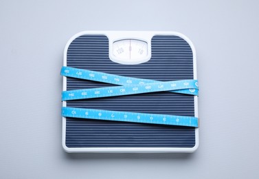 Photo of Scales and measuring tape on light grey background, top view