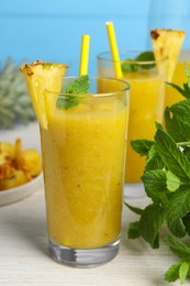 Photo of Tasty pineapple smoothie and mint on white wooden table