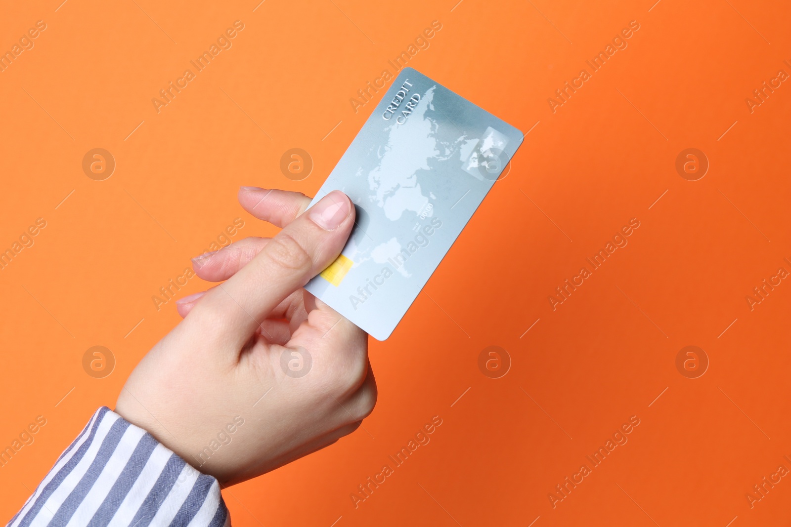 Photo of Woman holding credit card on orange background, closeup