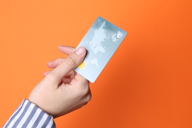 Photo of Woman holding credit card on orange background, closeup