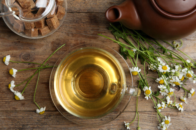 Flat lay composition with tea and chamomile flowers on wooden table