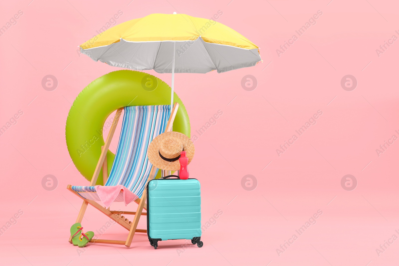 Photo of Deck chair, umbrella, suitcase and beach accessories against pink background, space for text. Summer vacation