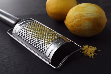 Grater and fresh lemons on black table