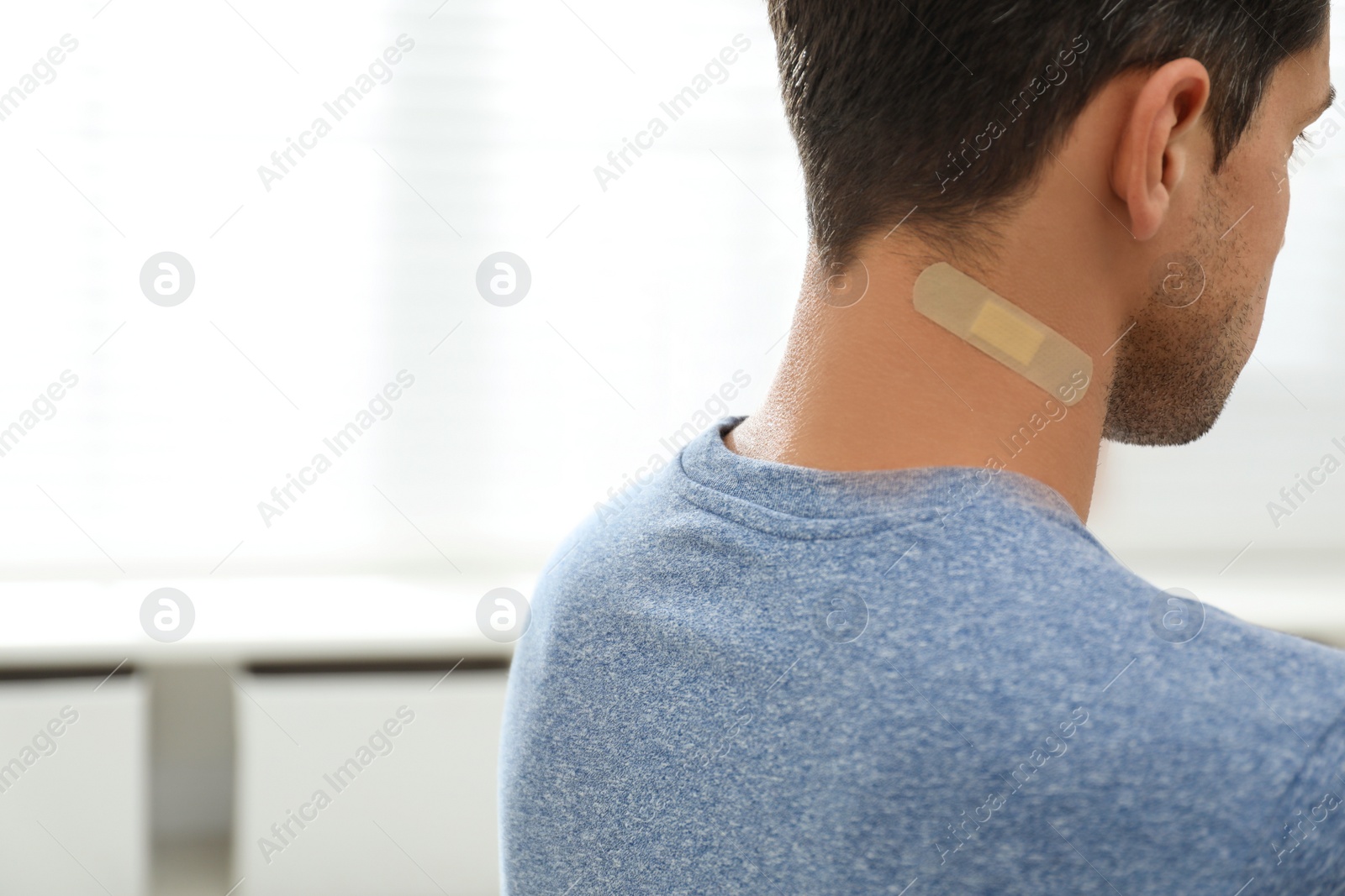 Photo of Man with sticking plaster on neck indoors, closeup