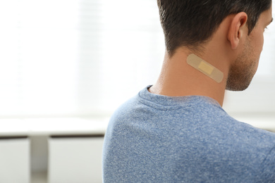 Photo of Man with sticking plaster on neck indoors, closeup