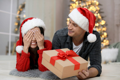 Photo of Man presenting Christmas gift to his girlfriend at home