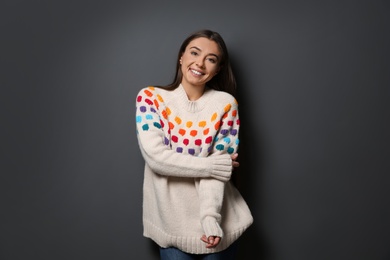 Photo of Beautiful young woman in warm sweater on dark background
