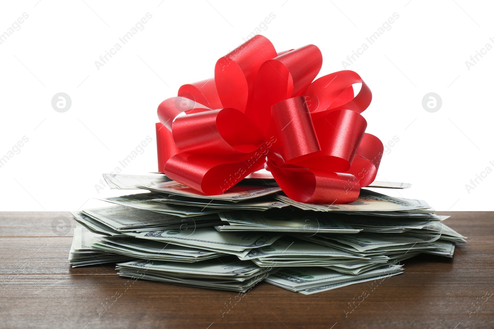 Pile of dollar bills with red bow on wooden table against white background Photo of Pile of dollar bills with red bow on wooden table against white background