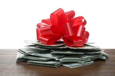 Photo of Pile of dollar bills with red bow on wooden table against white background