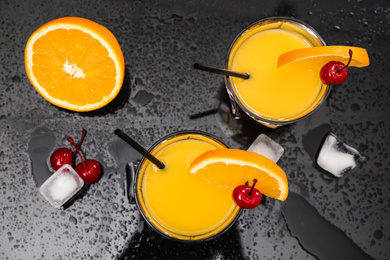 Photo of Fresh alcoholic Tequila Sunrise cocktails on black table, flat lay