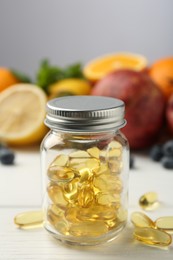 Photo of Vitamin pills in bottle and fresh fruits on white wooden table, closeup