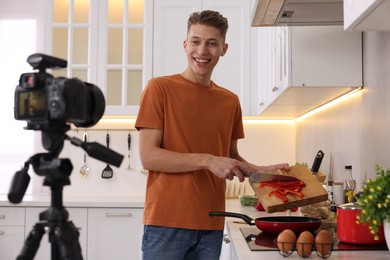 Smiling food blogger cooking while recording video in kitchen