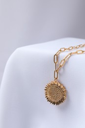 Photo of Stylish presentation of necklace on white cloth, closeup