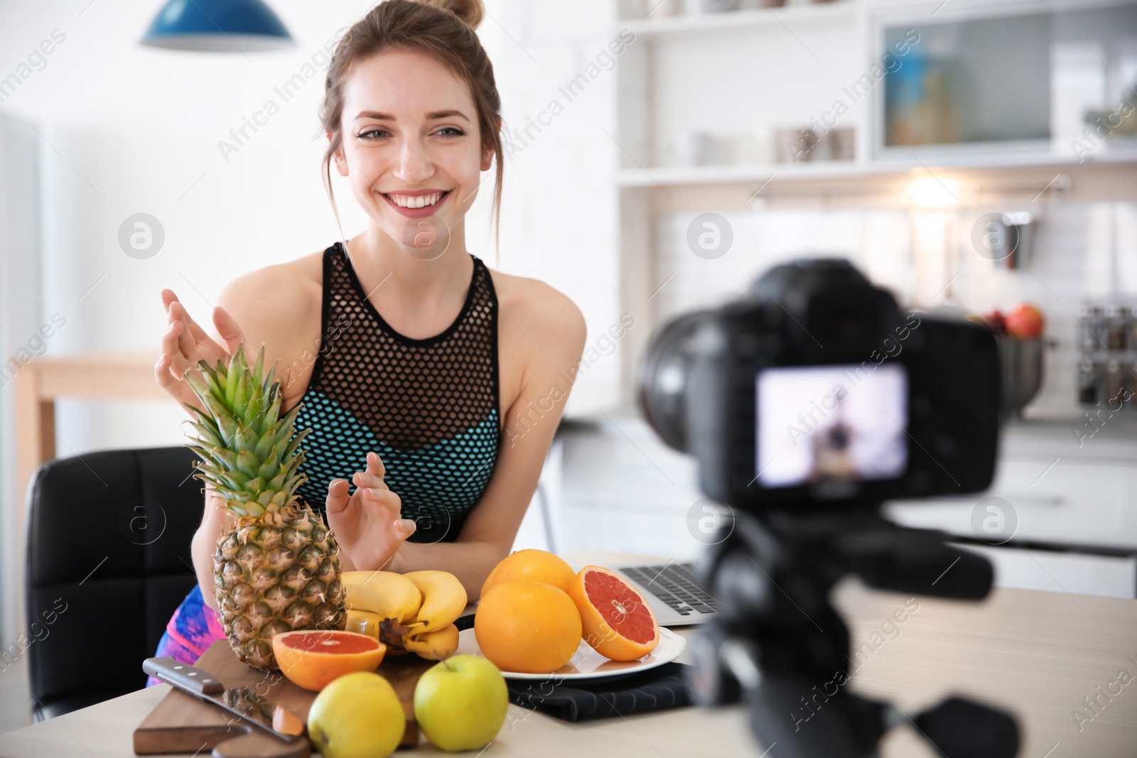 Photo of Young blogger with fruits recording video on kitchen