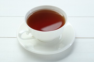 Photo of Aromatic tea in cup on white wooden table