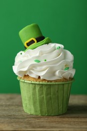 Photo of St. Patrick's day party. Tasty cupcake with leprechaun hat topper on wooden table, closeup