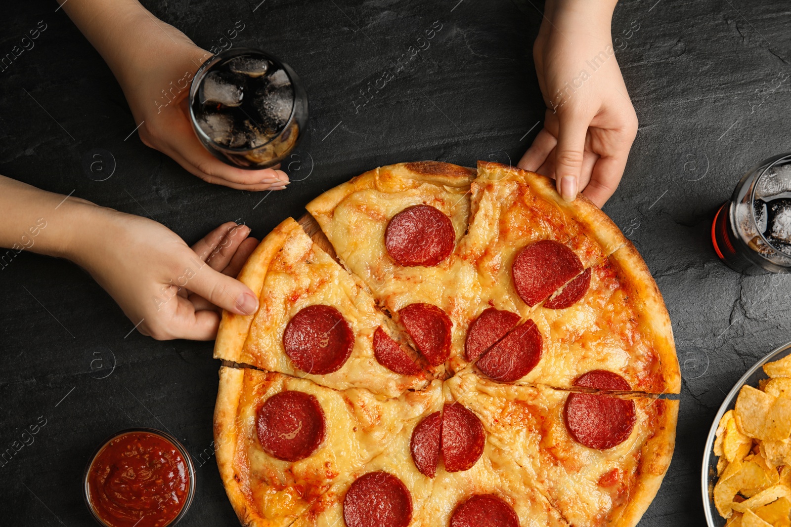 Photo of Women taking tasty pepperoni pizza at grey table, top view