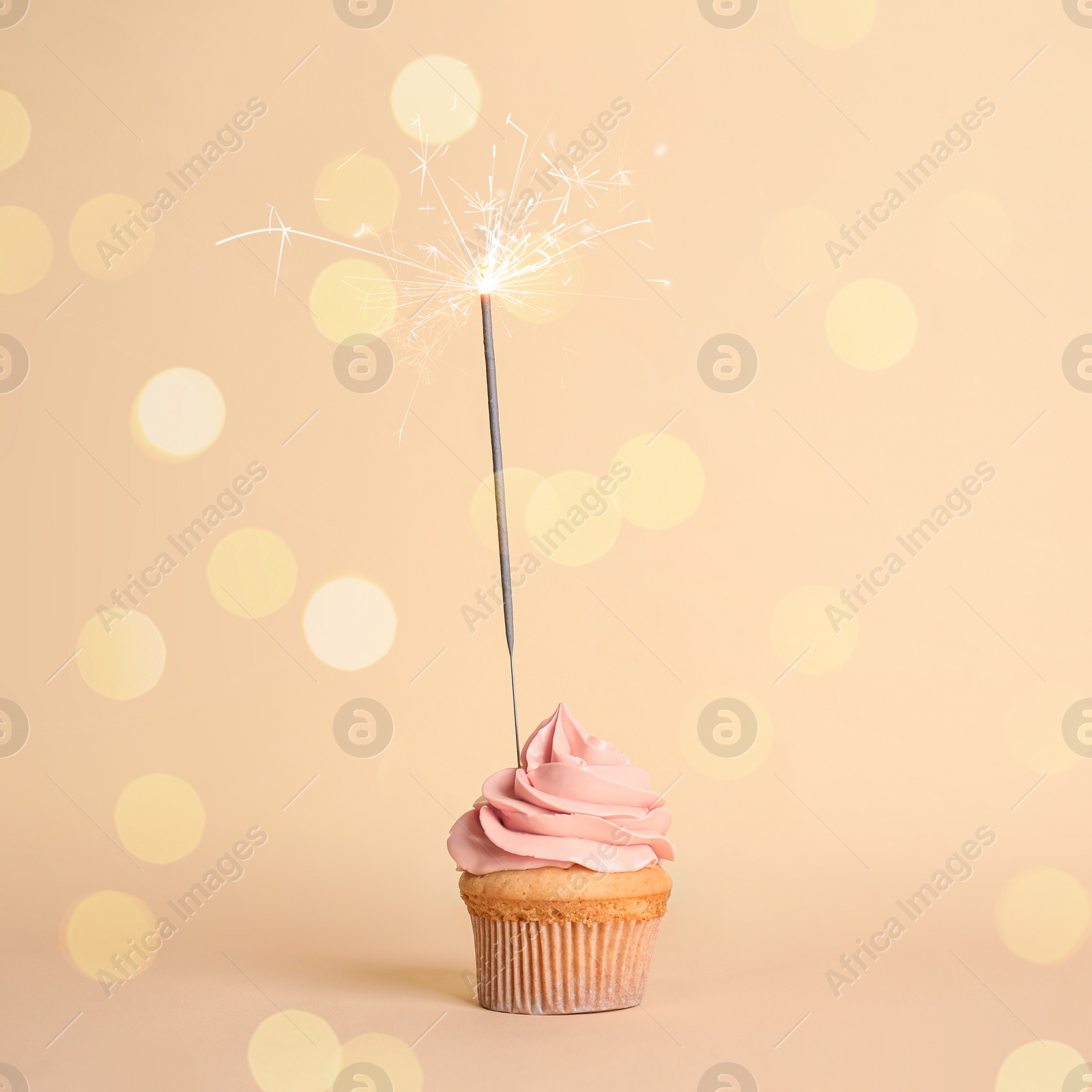 Image of Birthday cupcake with sparkler on beige background