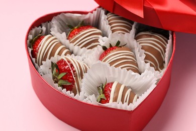 Photo of Heart shaped box with delicious chocolate covered strawberries on pink background, closeup