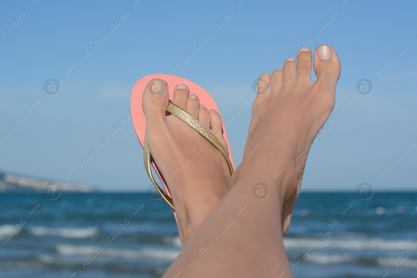 Photo of Woman wearing stylish flip flop near sea, closeup