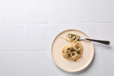 Photo of Heart made of tasty spaghetti, fork, olives and cheese on white tiled table, top view. Space for text