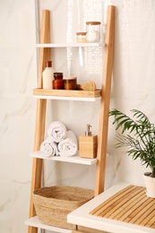 Photo of Soft towels and different toiletries on decorative ladder in bathroom. Interior design