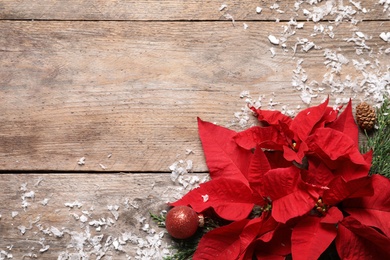 Flat lay composition with poinsettia and space for text on wooden background. Traditional Christmas flower