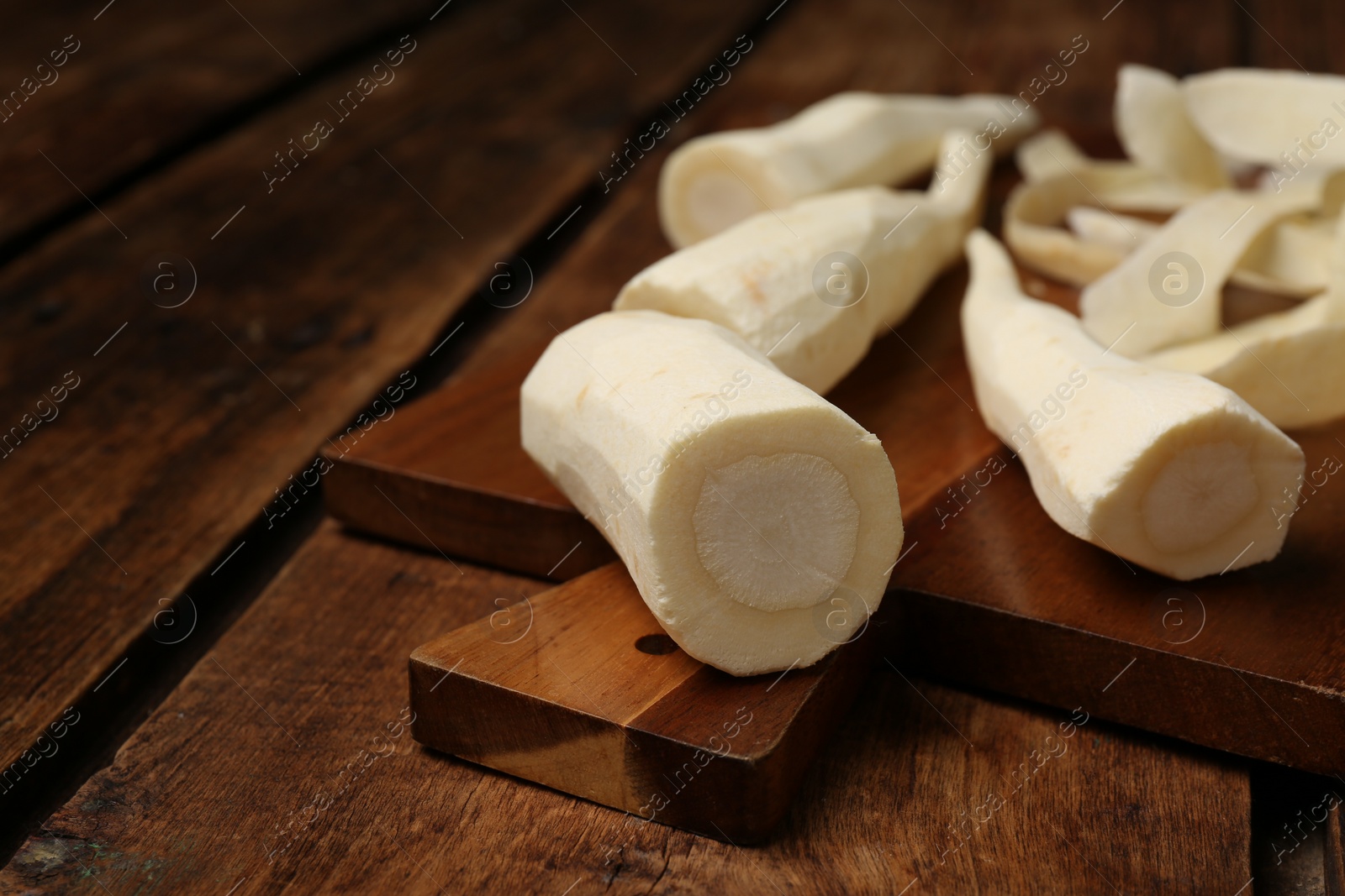 Photo of Whole and cut fresh ripe parsnips on wooden table. Space for text