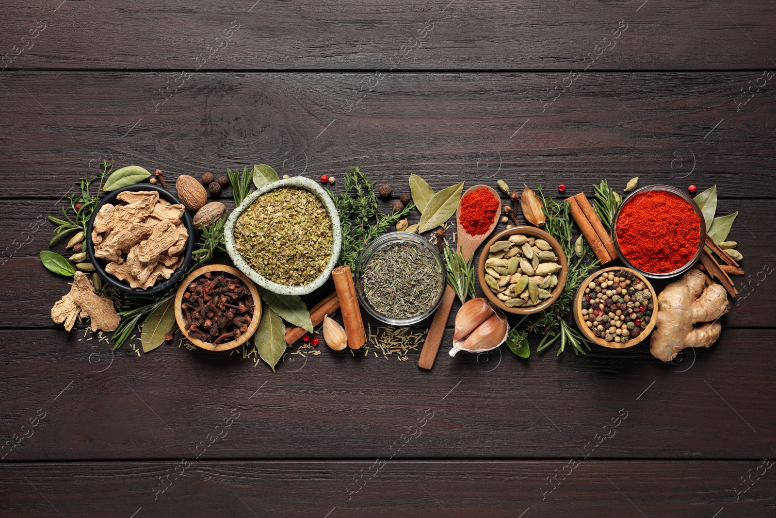 Photo of Different natural spices and herbs on wooden table, flat lay