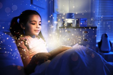 Image of Little girl reading fairy tale in dark bedroom