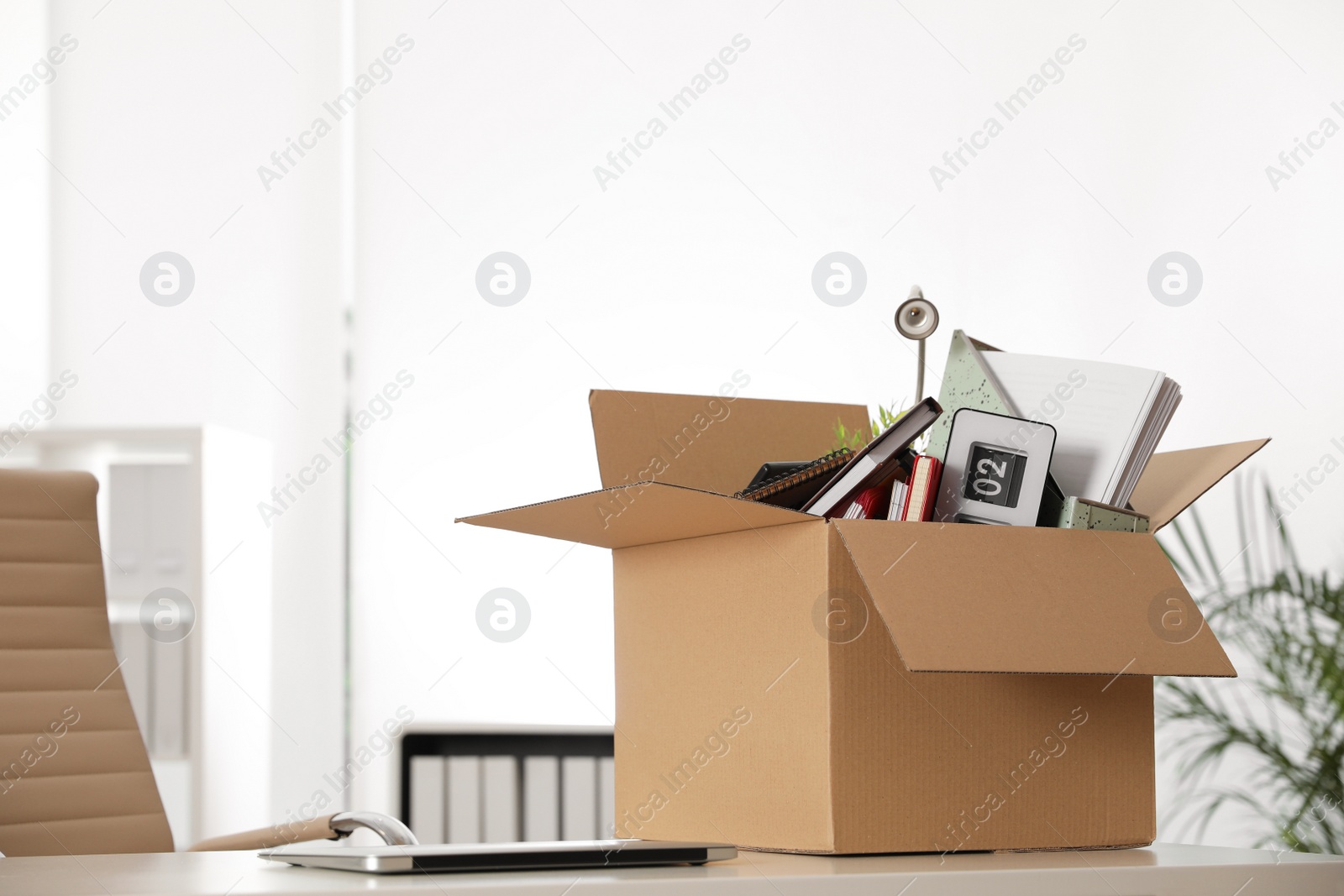 Photo of Cardboard box full of stuff on table in office