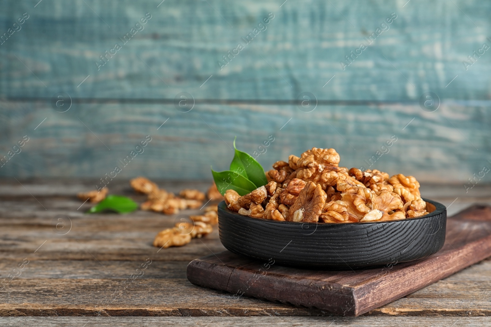 Photo of Plate with tasty walnuts on wooden table. Space for text