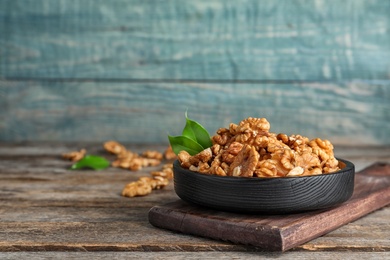 Plate with tasty walnuts on wooden table. Space for text