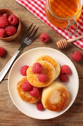 Delicious cottage cheese pancakes with raspberries on wooden table, flat lay