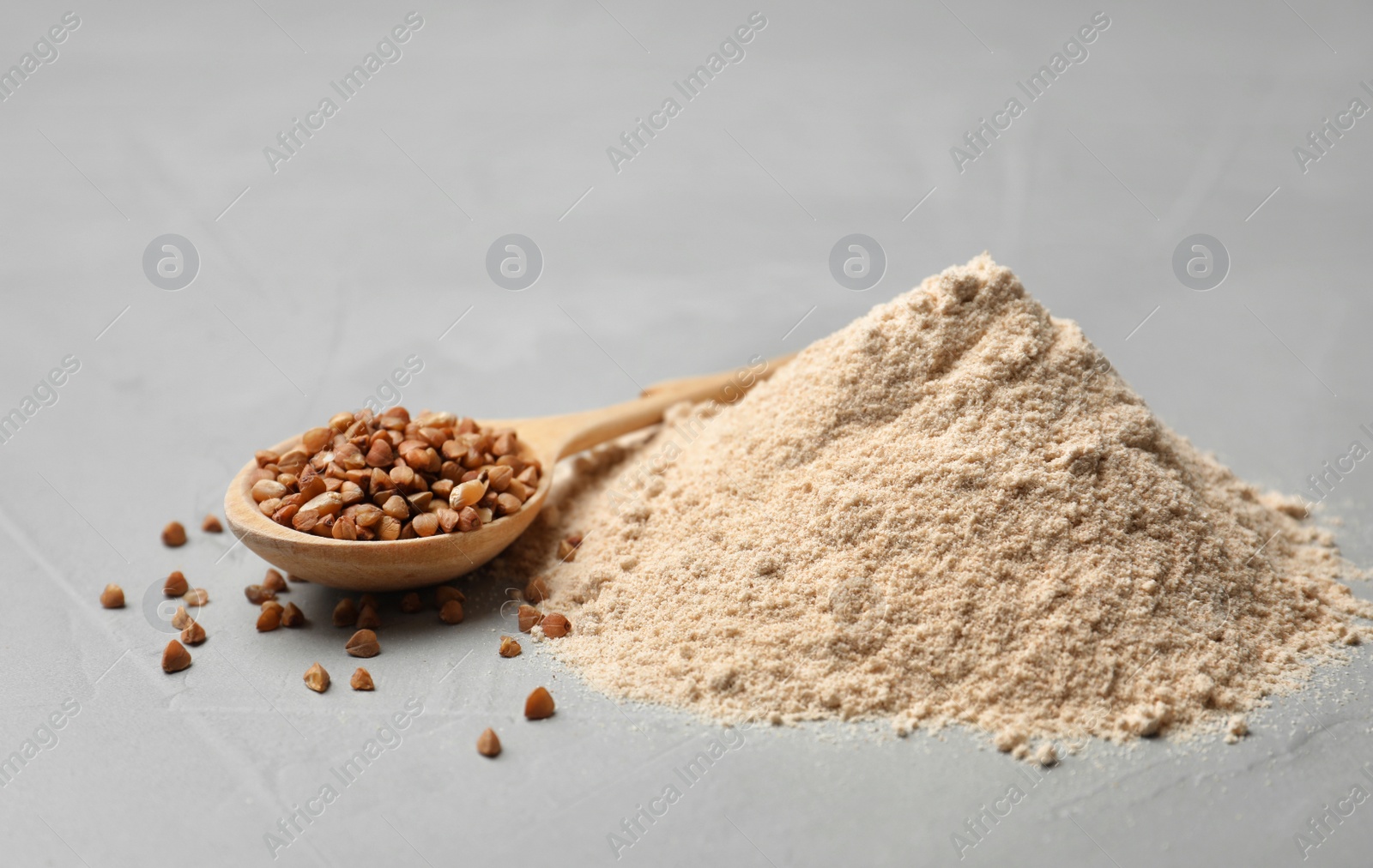 Photo of Pile of flour and buckwheat in spoon on table