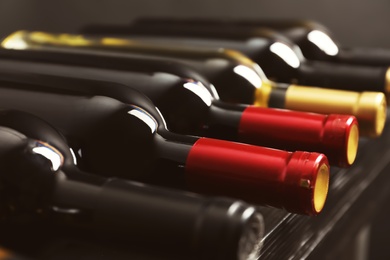 Photo of Bottles with delicious wine on shelf, closeup. Professional sommelier