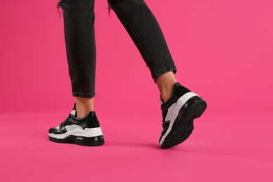 Woman wearing sneakers on pink background, closeup