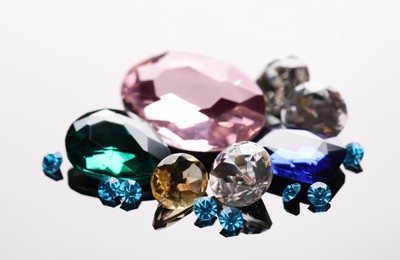 Different beautiful gemstones for jewelry on mirror surface, closeup