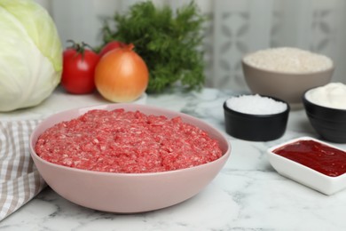 Photo of Set of ingredients for preparing stuffed cabbage rolls on white marble table