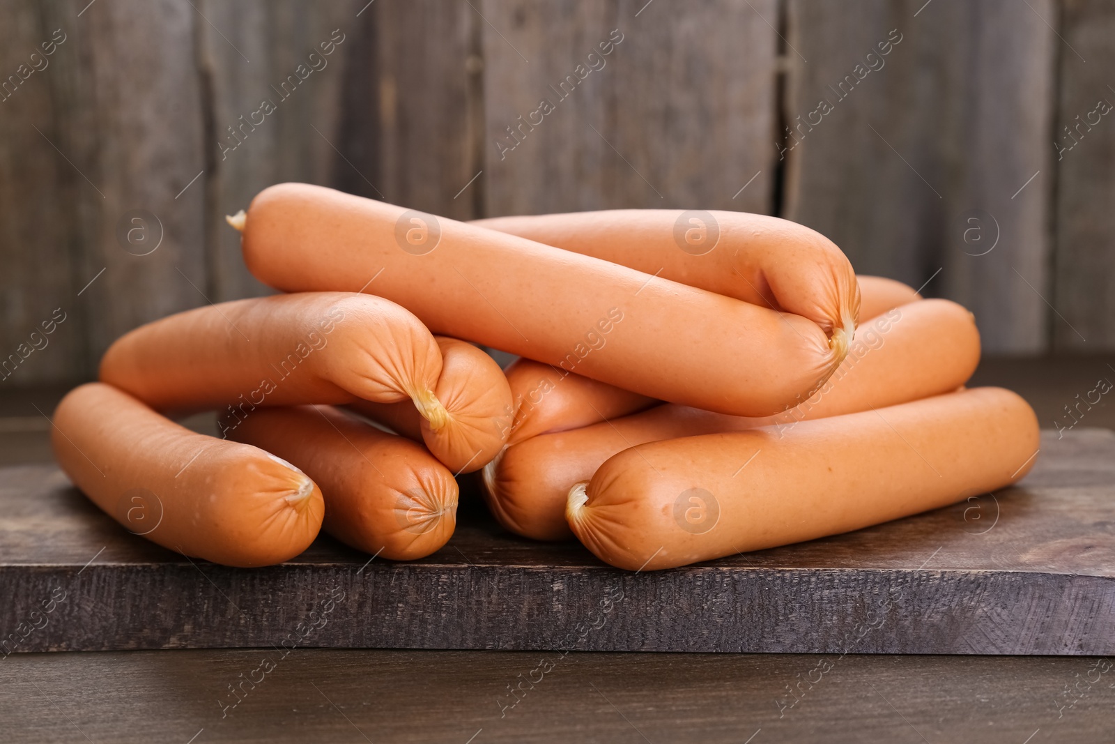 Photo of Many fresh delicious sausages on wooden table