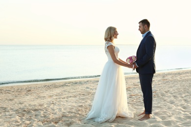 Wedding couple holding hands together on beach. Space for text