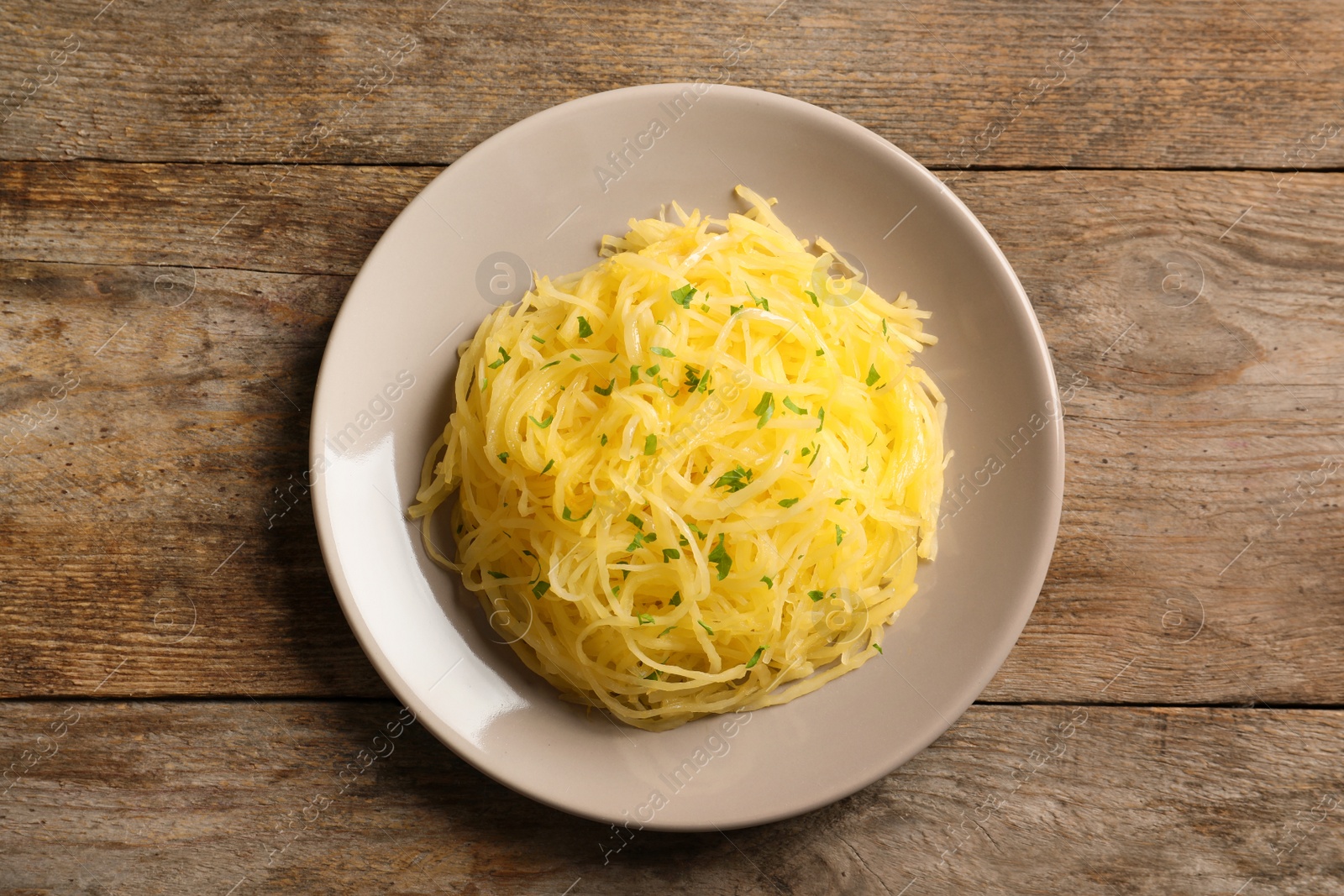 Photo of Plate with cooked spaghetti squash on wooden table, top view