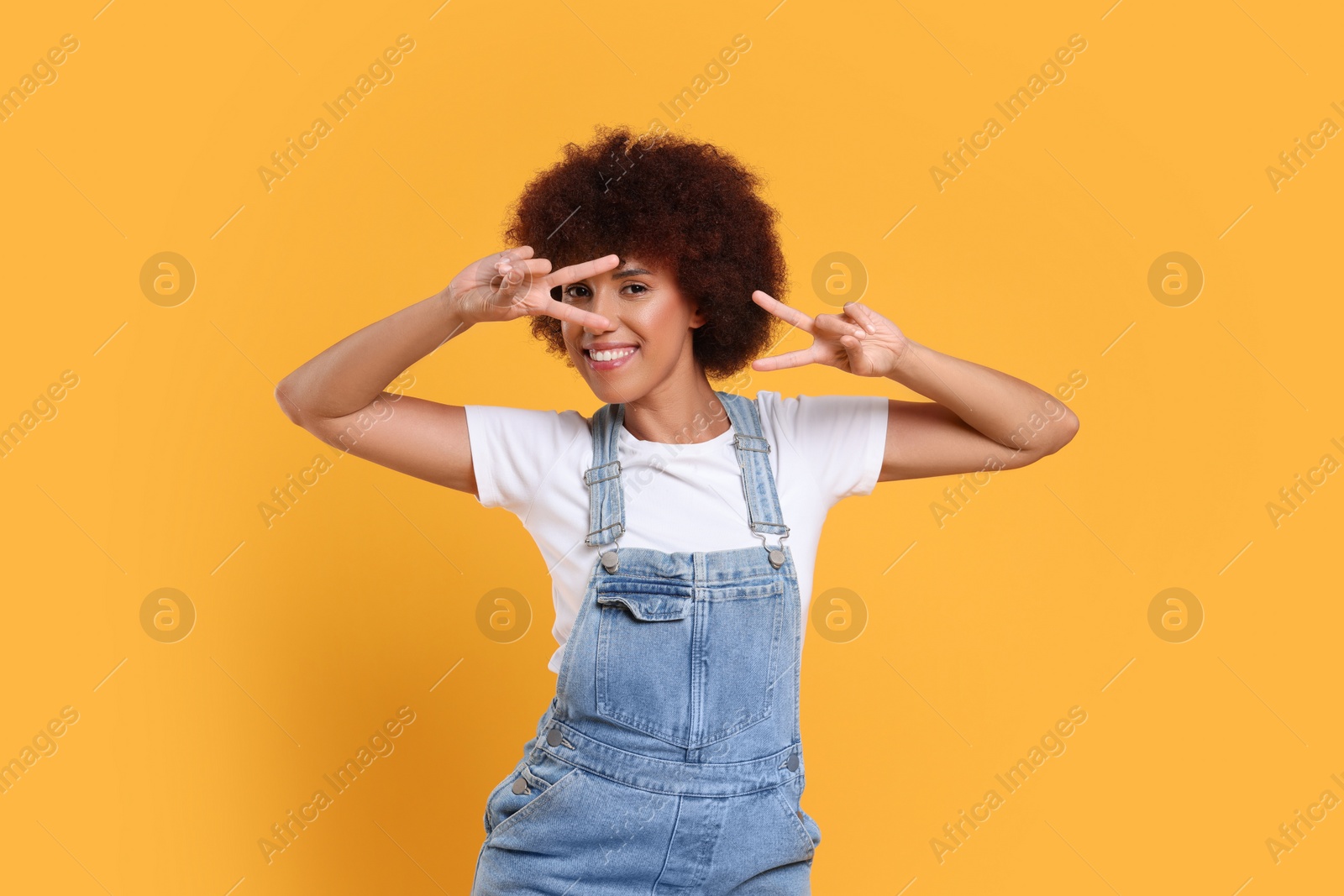 Photo of Happy young woman dancing on orange background