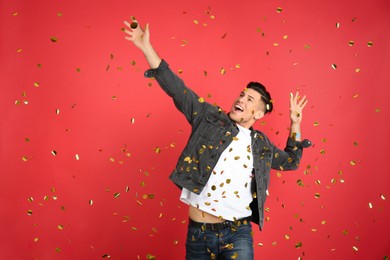 Photo of Emotional man and falling confetti on red background