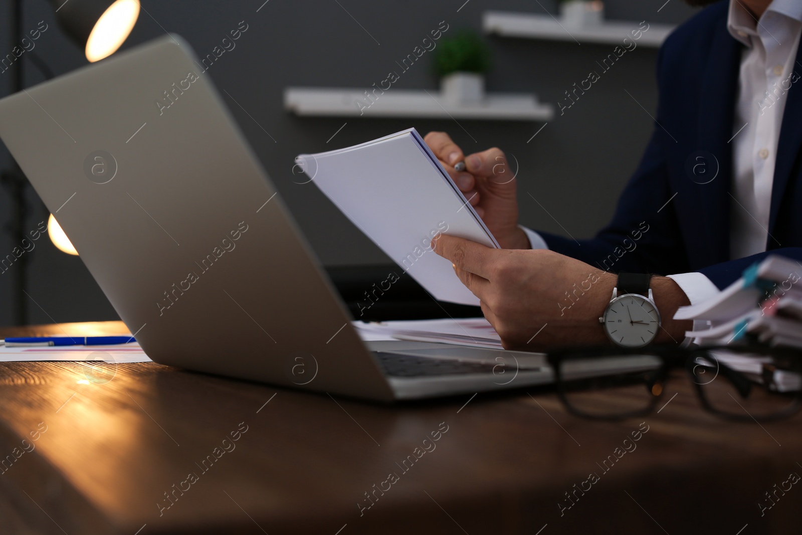 Photo of Businessman working with laptop and documents at table, closeup