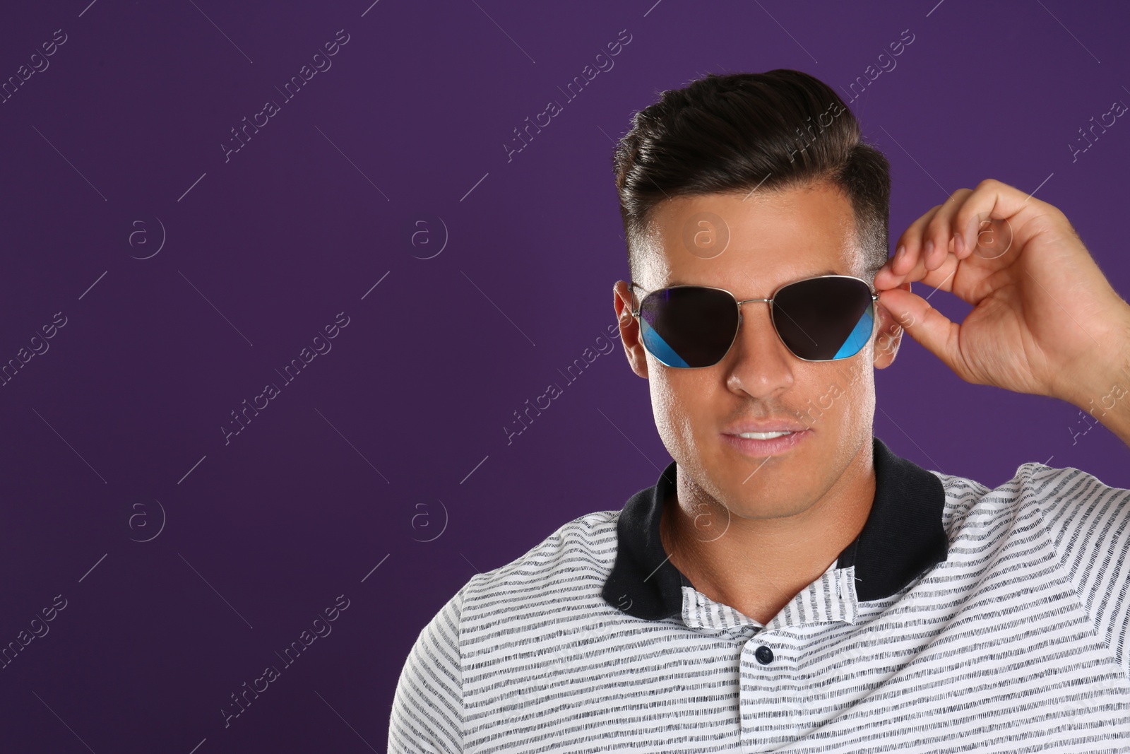 Photo of Handsome man wearing sunglasses on purple background. Space for text