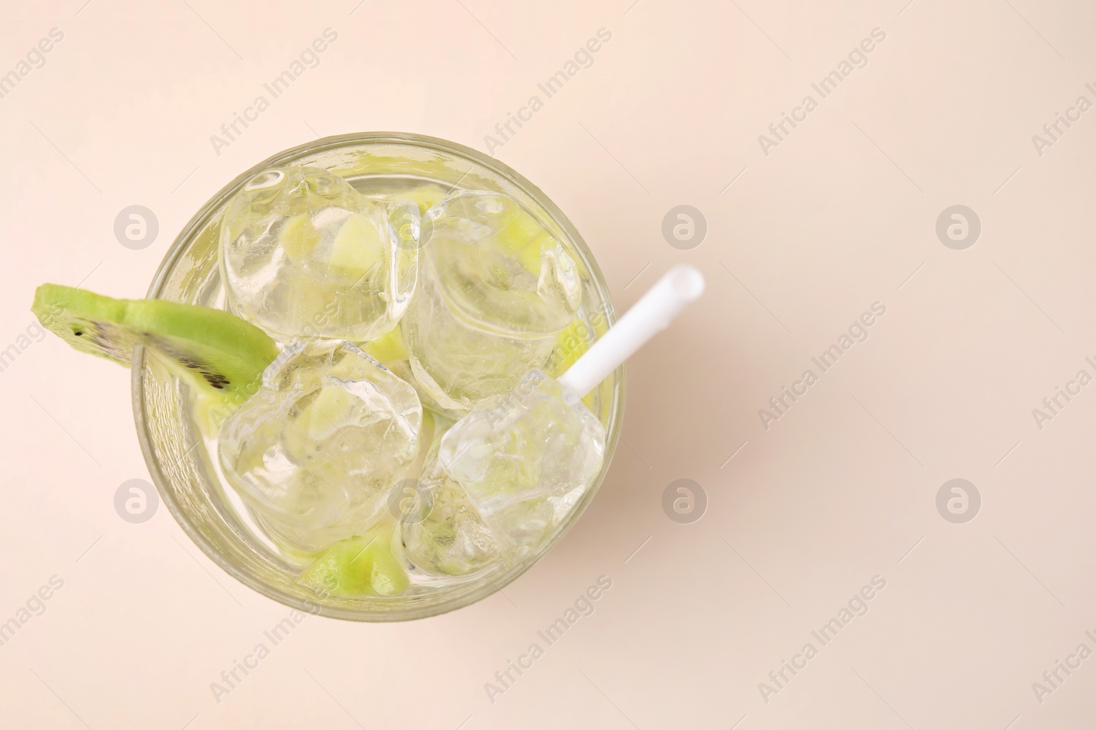 Photo of Glass of refreshing drink with kiwi on beige background, top view. Space for text