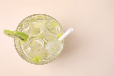 Glass of refreshing drink with kiwi on beige background, top view. Space for text